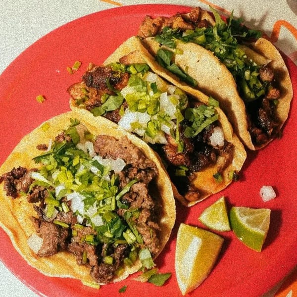 Three El Santo Gallo Taqueria tacos with meat, cilantro, and onions, served with lime wedges on a red plate.